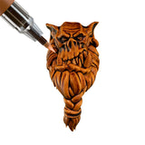 Paint marker being applied to a miniature face on a white background