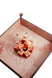Cubed red and white dessert on a decorative tray with a white background